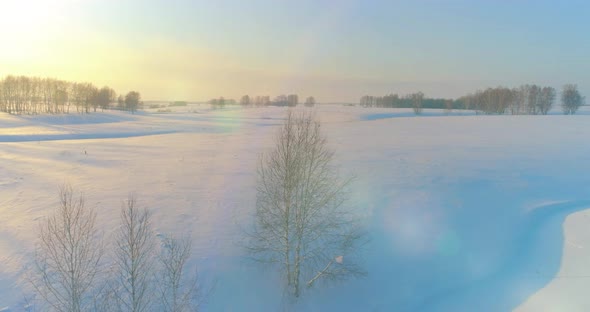 Aerial View of Cold Arctic Field Landscape Trees with Frost Snow Ice River and Sun Rays Over Horizon