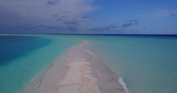 Daytime fly over clean view of a sandy white paradise beach and blue water background in colourful 4