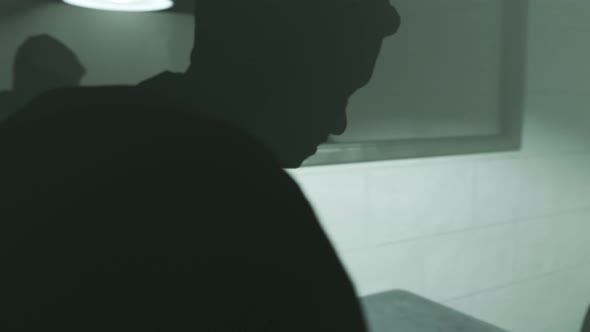Interrogation room with dark silhouettes. Detective interrogates handcuffed man