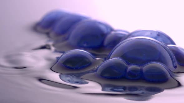 Blue bubbles on water surface popping, Slow Motion