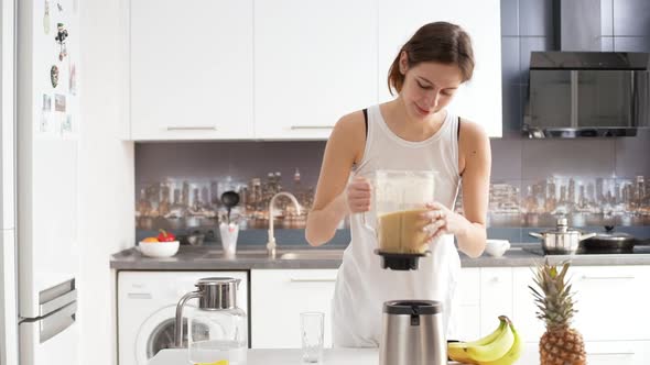 Young Attractive Caucasian Female Making Fruit Smoothie Using Blender Then Drinking It with Pleasure