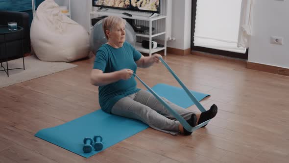 Old Woman Stretching Arms and Legs with Resistance Band