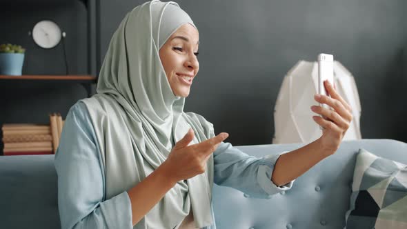 Beautiful Girl in Hijab Chatting and Waving Hand During Video Call From Apartment