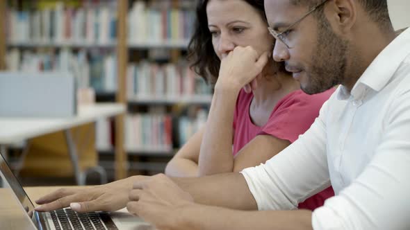 Concentrated Young People Reading Information From Laptop