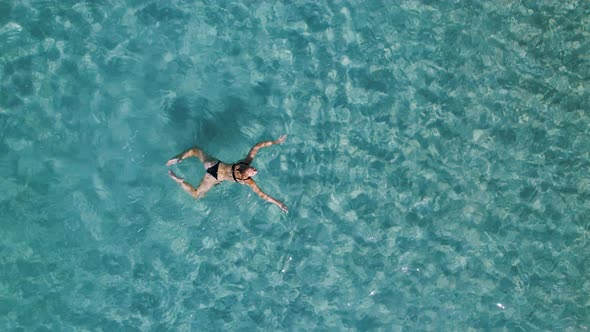 A Woman Swims in Blue Sea Water in the Bay