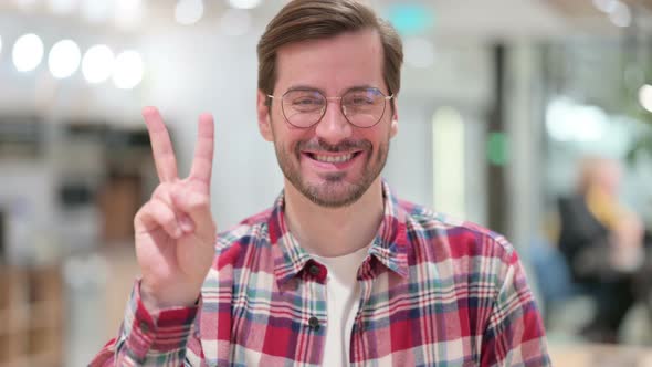 Portrait of Successful Male Designer Showing Victory Sign with Hand