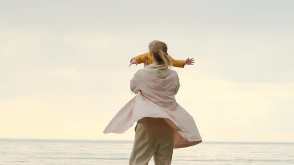 Happy Mom and Daughter on Background of Sea or Ocean at Sunset