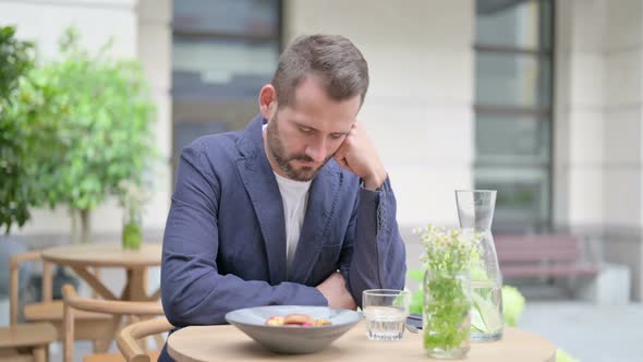 Tired Man Taking Nap While Sitting in Outdoor Cafe