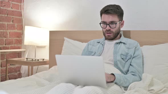 Young Male Designer Reacting To Failure on Laptop in Bed