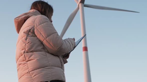 A Wind Turbine Inspector Standing with Tablet and Controls the System