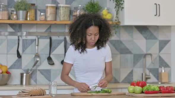 African Woman Feeling Tired While Cutting Vegetables in Kitchen