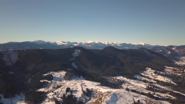 Aerial view of small village with scattered houses on snow covered hills in winter