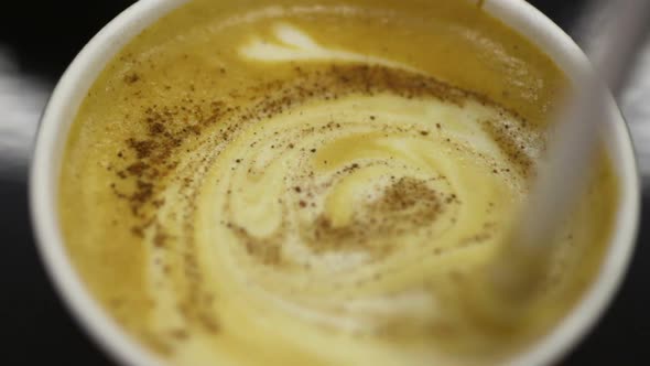 Person Stirring Aromatic Coffee With Fluffy Foam, Cup of Hot Cappuccino Closeup