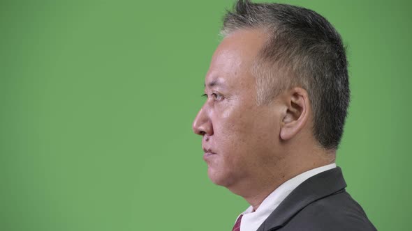 Profile View of Mature Japanese Businessman Against Green Background