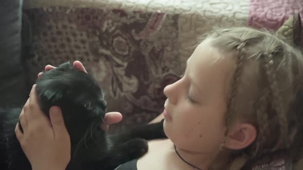 Girl Lies on Couch with Her Cat Affectionately Hugging and Kissing Him