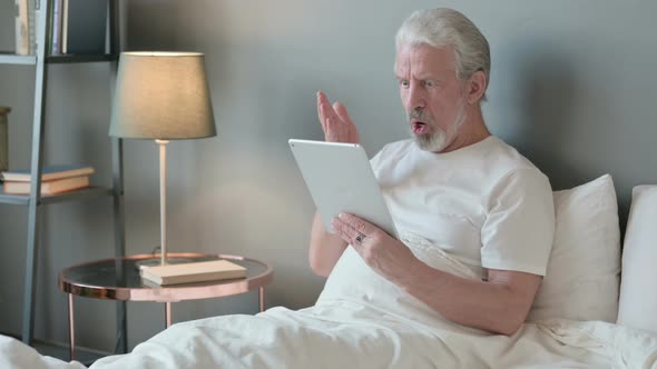 Old Man Reacting To Loss on Tablet in Bed 