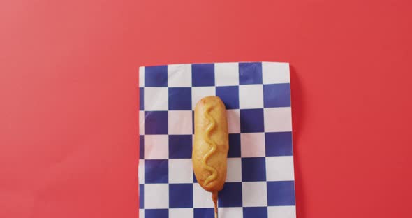 Video of corn dog with mustard on a red surface