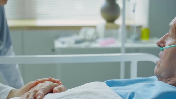 Sick Old Man Talking with Careful Nurse in Hospital Ward