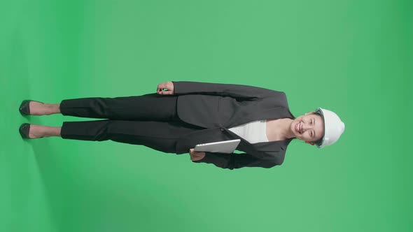 Full Body Of Asian Female Engineer With Safety Helmet Holding A Laptop In The Green Screen Studio