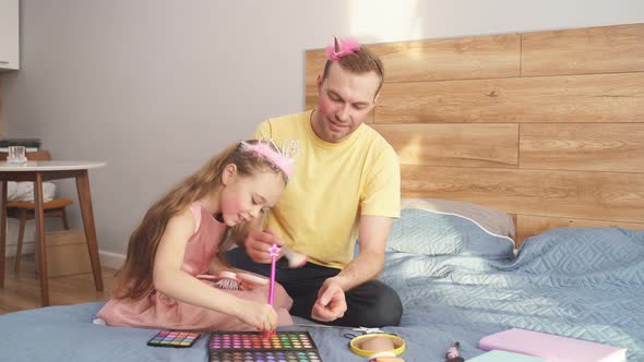 Young Man and His Child Daughter are Playing with Cosmetics at Home Do Makeup on Face