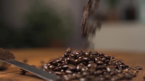 Roasted coffee beans falling onto a wooden surface.