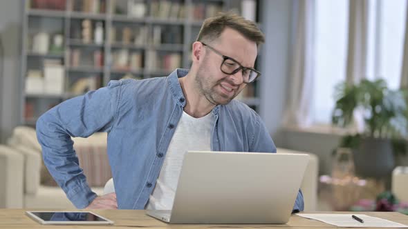 Tired Young Man Having Back Pain in Loft Office 