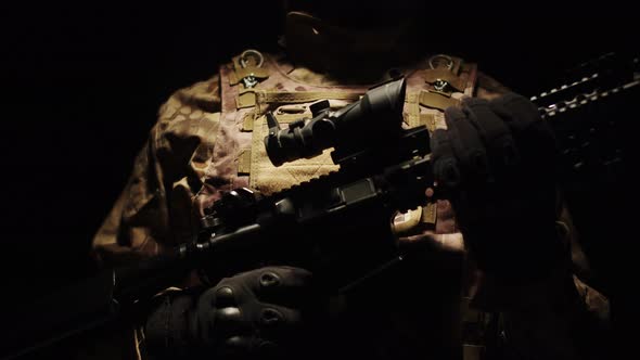 Closeup of Man Soldier in Military Uniform and with Rifle in Hands a Dark Studio Background