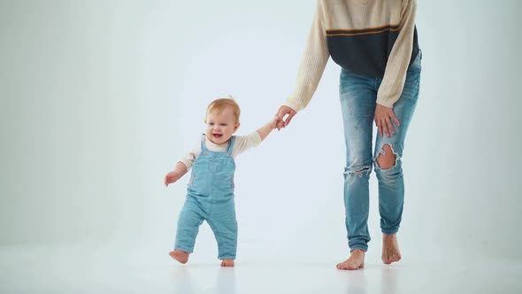 Mom holds the baby by the hand and teaches to walk. studio slow motion