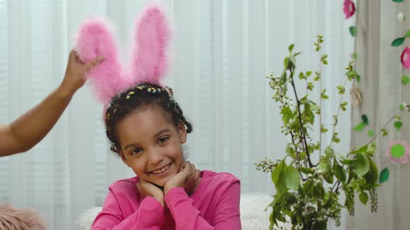 A Cute Little Girl Looks in Funny Pink Bunny Ears Looks at the Camera and Smiles