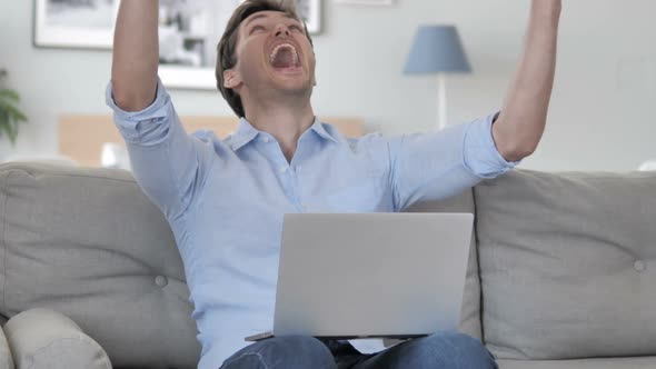 Handsome Young Man Celebrating Success on Laptop