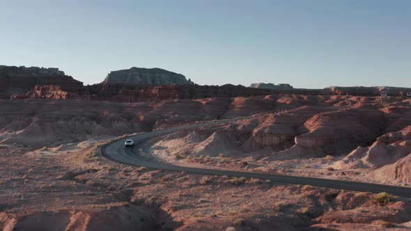 Drone Following Vehicle with Tourists Traveling Famous Goblin Valley at Sunrise