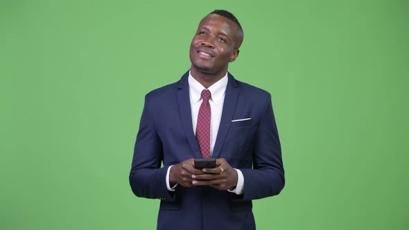 Young Happy African Businessman Thinking While Using Phone