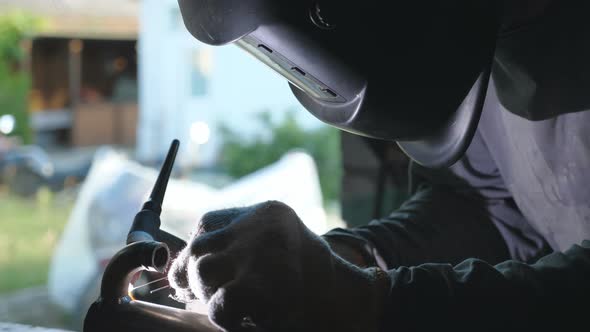 Male Mechanic in Protective Mask Doing Welds Work Using Professional Equipment