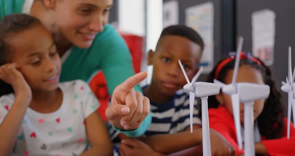 Front view of Caucasian female teacher teaching student about windmill in the classroom 4k