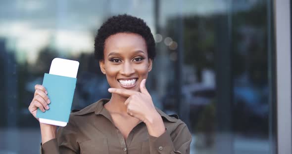 Portrait Happy Smiled African Millennial Woman Dancing in Airport Showing Airplane Ticket Passport