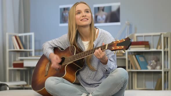 Young Lady Playing Guitar in Her Room, Writing Song, Dreaming of Music Career