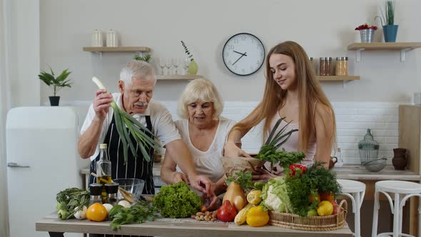 Senior Couple in Kitchen Receiving Vegetables From Granddaughter. Healthy Raw Food Nutrition