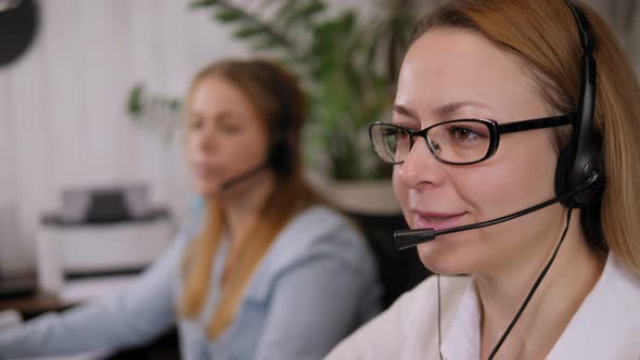 Closeup of a Smiling Woman in Glasses with Headphones Working in a Call Center