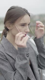 Vertical Video. Beautiful Girl in Glasses and a Gray Suit. Slow Motion