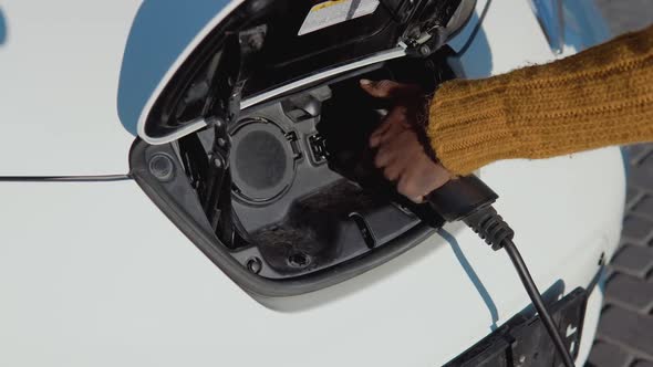 A Darkskinned Male Driver Disconnects the Electric Car From the Power System