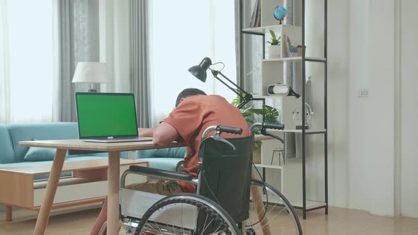 Tried Asian Boy Sitting In A Wheelchair Yawn And Sleep While Using Laptop With Green Screen At Home