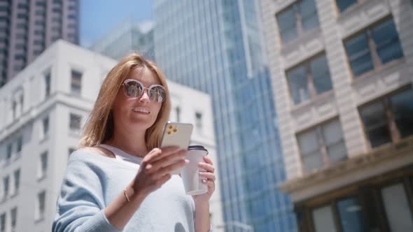 Closeup Cheerful Girl Standing with Cup Coffee Smartphone in Urban Background