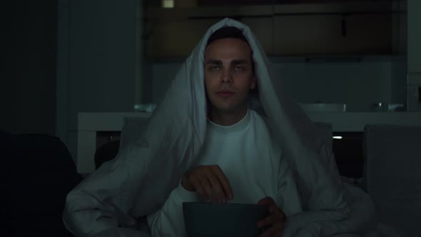 Young Guy Watching Thriller Movie at Home. Handsome Man Holding Popcorn Bowl While Sitting on Couch