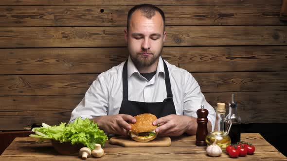 Bearded Young Male Chef Eats Homemade Burger