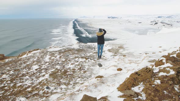 Young Woman Tourist Takes Pictures at the Top of the Cliff Around Reynisfjara Beach and Dyrholaey