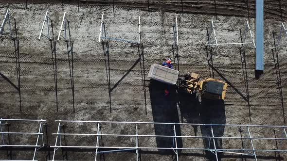 Top View of an Excavator Moving a Massive Box with Solar Panels in the Field