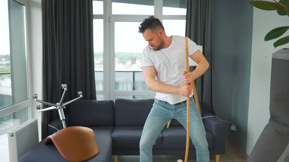 Man Cleaning the House and Having Fun Dancing with a Broom