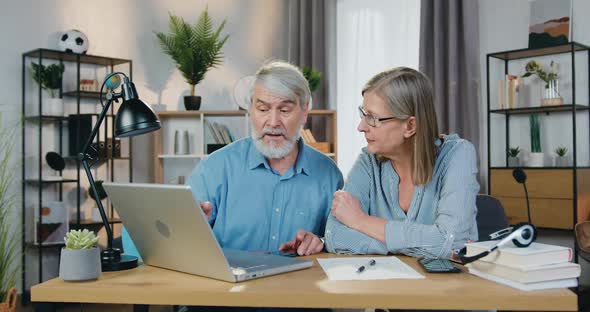 Couple Pointing on Laptop Screen and Discussing Something