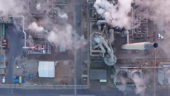 Aerial Top Down view during sunrise of steel factory. High above factory smoke coming from chimney c