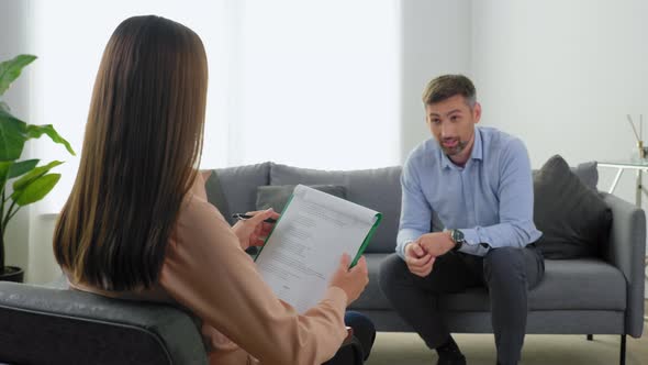 Unfocused Smiling Man Patient with Mental Health Problems Talking to Therapist